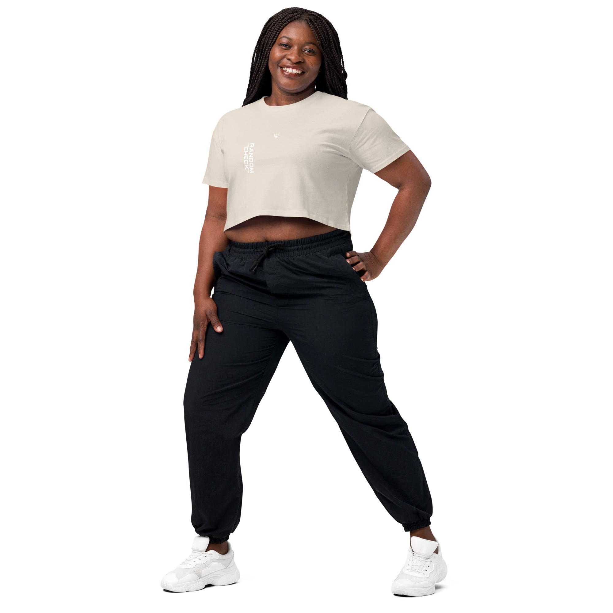 Woman wearing a beige crop top and black pants on a white background